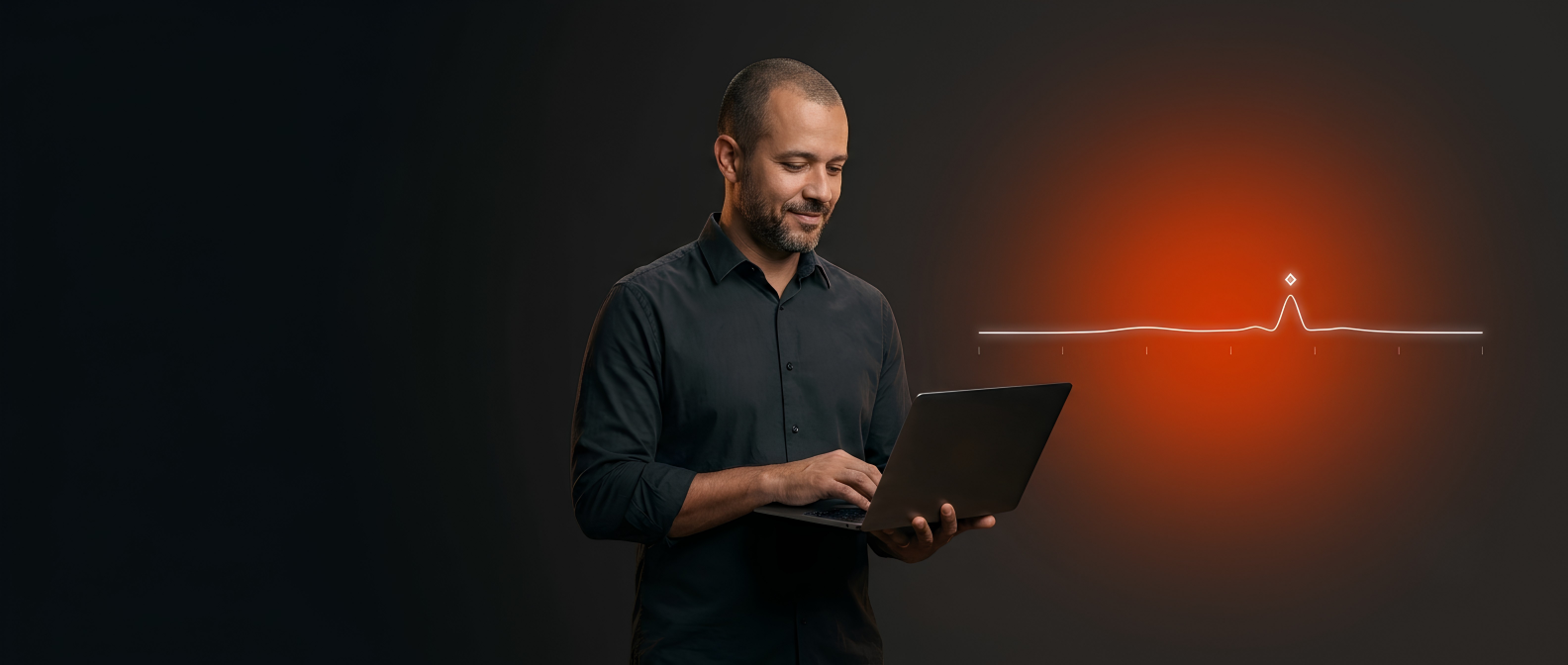Homem de camisa usando um notebook ao lado de uma linha luminosa de monitoramento com um pico em destaque, sobre fundo escuro.